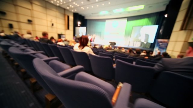 People sit on rows of chairs in auditorium during conference