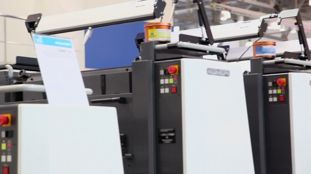 Row of printing equipment with cans of paint on it