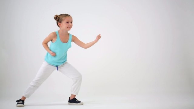 Little girl have fun while doing exercises with fighting elements