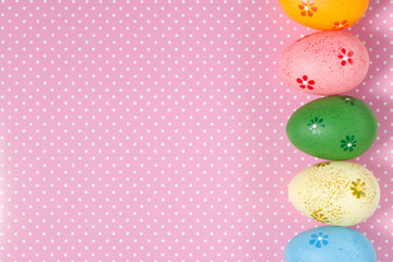 Colorful easter eggs on pink polka dots background. Top view, flat lay with copy space for text. Easter background.