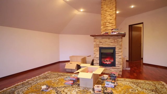 Room with box and books on carpet and fireplace 