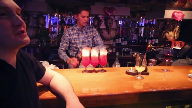 Young handsome bartender makes cocktails for visitor
