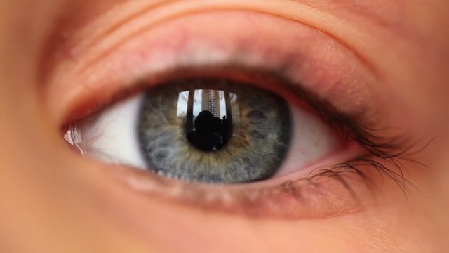 Left blue eye with reflection of house blinks, close-up 