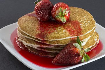 Pancakes with fresh strawberries and strawberry syrup.