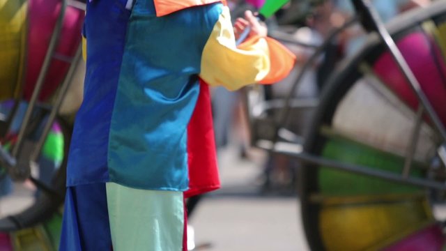 Hands of clown juggler in colored clothes and moving big bike