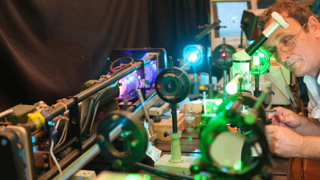 system of electronic devices with lasers and magnifying glasses and scientist who is adjusting them