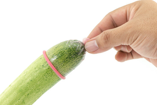 Man's hand removes the condom from cucumber