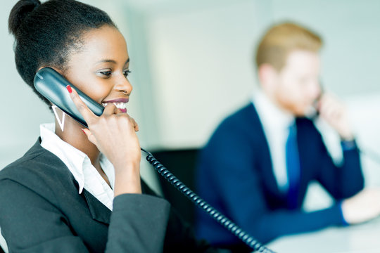 A beautiful, black, young woman working in a call center in an o