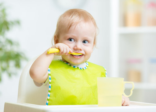 baby child sitting in chair with a spoon