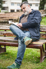 Attractive bearded man reading in a park