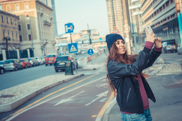 Fototapeta premium Beautiful girl taking a selfie in the city streets