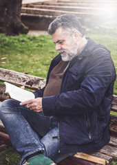 Attractive bearded man reading in a park