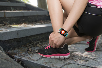 Sport woman tying shoelaces wearing health sensor smartwatch wit