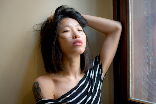 Beautiful sensual asian woman posing thoughtful at window