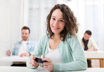 Young attractive student using smartphone during classes