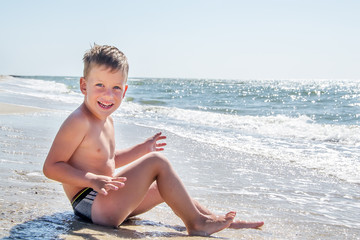 Cute little boy sitting at ocean beach