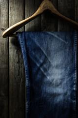 Blue jean with wood hanger on wood background, low key image