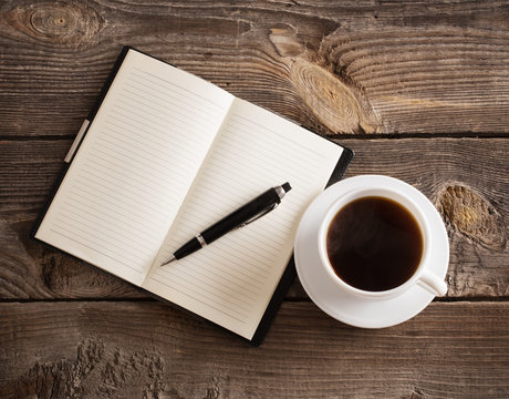 notebook with pen and coffee on old wooden table