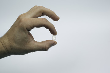 human hand hold one pill in fingers