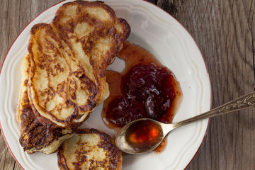 Plate with pancakes and jam metal spoon top view