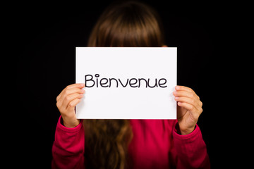 Child holding sign with French word Bienvenue - Welcome