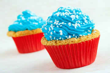Two cupcakes with blue icing and coarse sugar