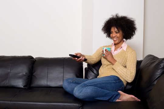 young african american woman watching television with a coffee