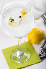 Gin tonic en copa de balón con twist de limón y bayas de enebro