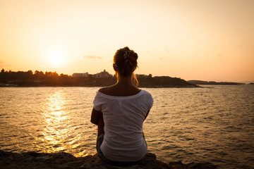beautiful model girl sitting on the rock by the sea