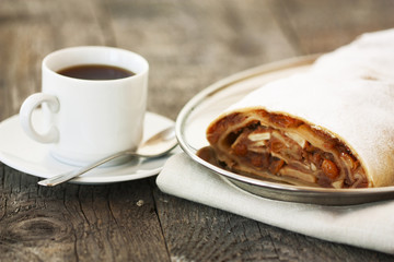 apple strudel and a cup of coffee on a wooden background