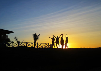 silhouette of friends jumping in sunset at beach