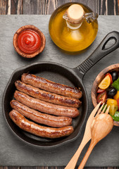 grilled sausages in a pan and vegetable salad. top view