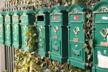 Reihe alter Briefkästen am Zaun einer Altbauvilla
