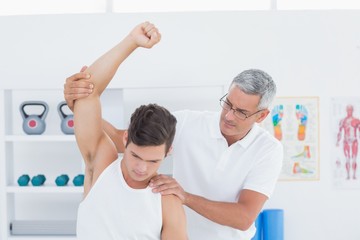 Fototapeta premium Doctor stretching a young man arm