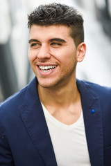 Handsome young man with blue eyes posing near a wall