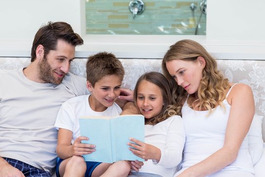Happy family on the bed reading book