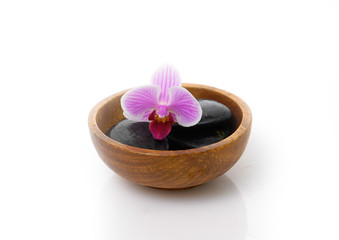 Fototapeta na wymiar black stones with pink orchid in wooden bowl 