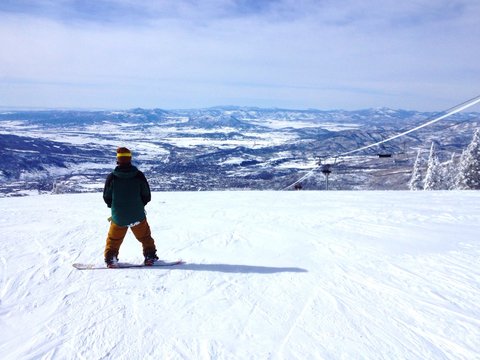 Snowboarder on top of a mountain enjoying the view