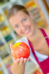 Fototapeta na wymiar Shop assistant holding up an apple