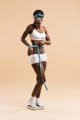 Woman standing on scale measuring waist with tape
