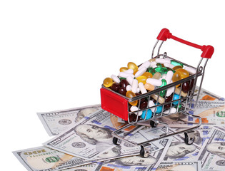 Obraz na płótnie Canvas Shopping cart full with pills over dollar bills, isolated