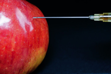 Hypodermic Needle Injecting a Red Apple