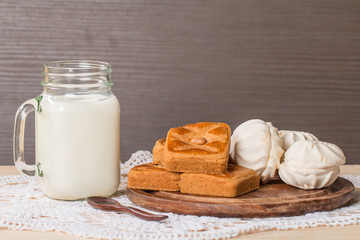 Fresh milk in glass and sweet cookies with zephyr