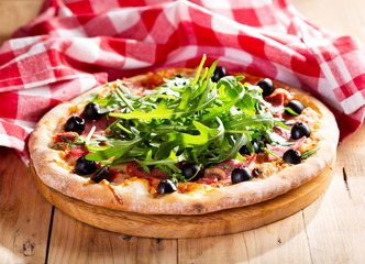 pizza with ham, salami and arugula salad
