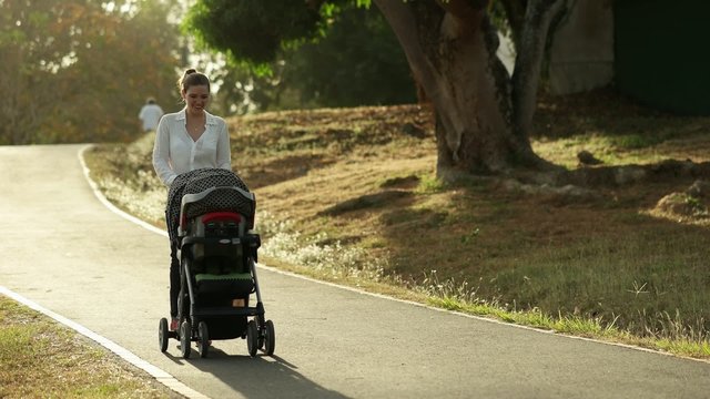 Woman Mother Mom With Toddler in Pushchair Walking In Park