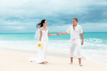 Happy groom and bride on the sandy tropical beach. Wedding and h