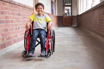 Fototapeta na wymiar Cute disabled mixed race pupil smiling at camera in hall
