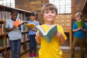 Cute pupils reading books at library