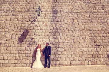 groom and bride in front of a big brick wall