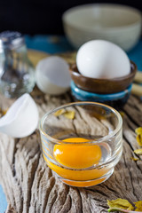 Still life broken white eggs and egg yolk on a wooden rustic bac